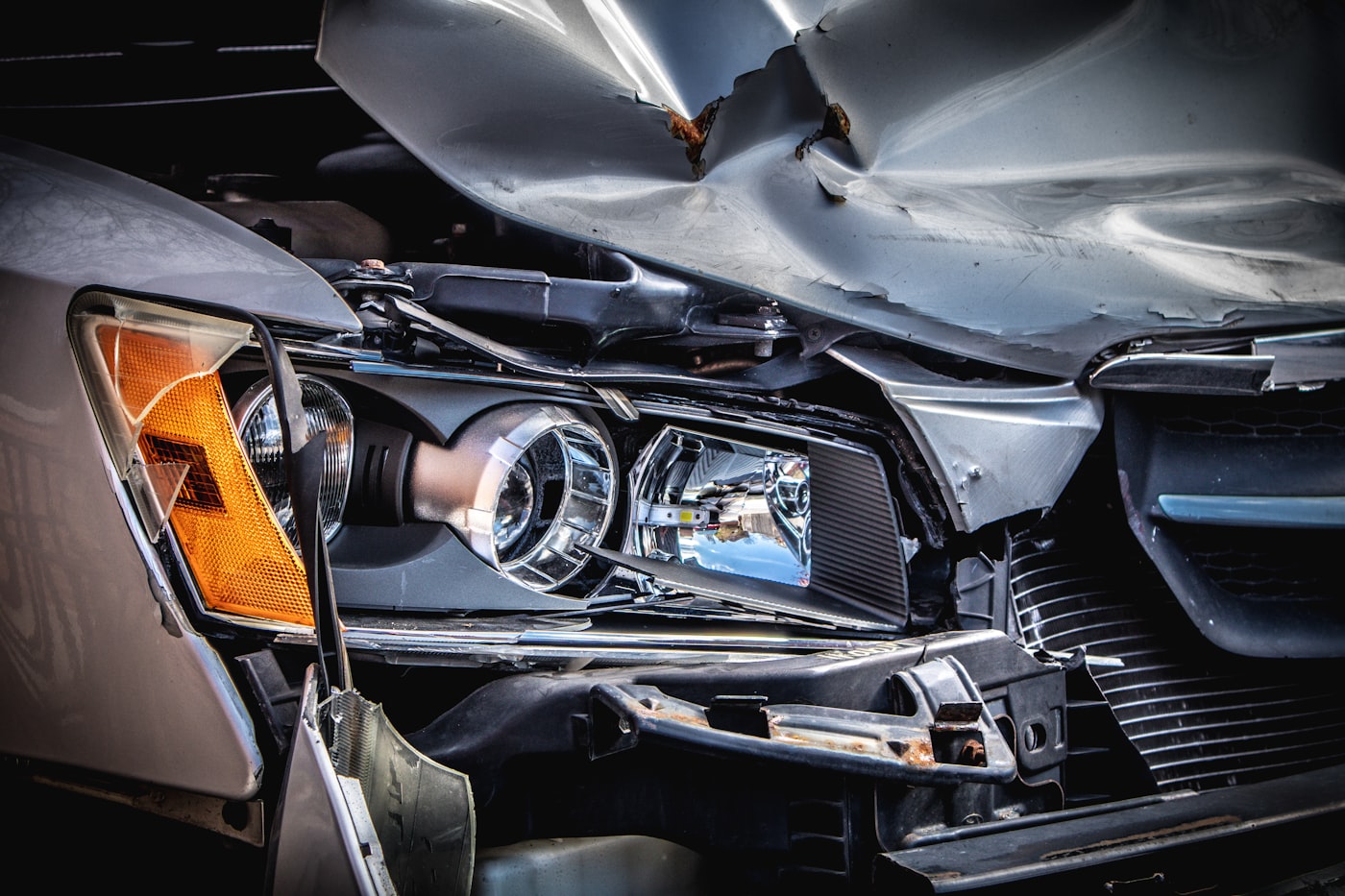 Damaged car after a nighttime collision with emergency lights in the background
