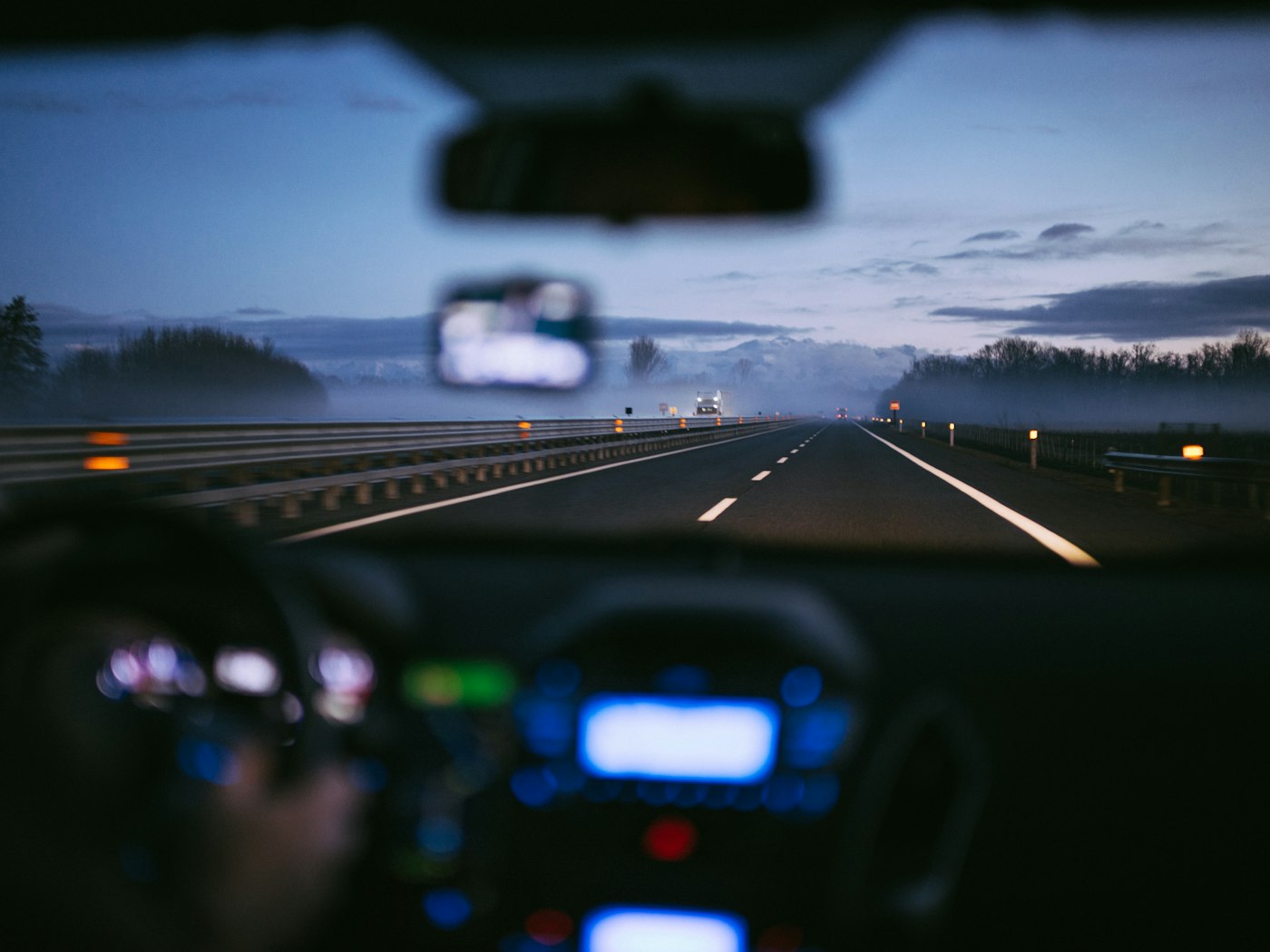 Blurred view through a windshield of headlights on a dark highway