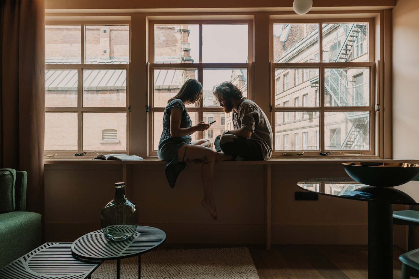 Two people in a quiet, caring conversation on a sofa with soft natural light