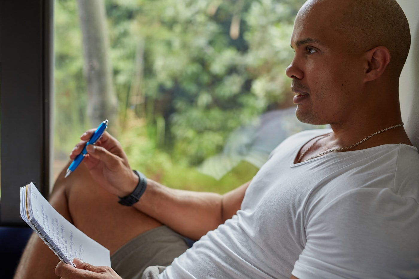 Person writing in a notebook by a window, thoughtfully planning with calm focus